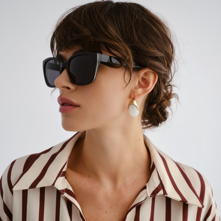 Female model wearing Teneriffe sunglasses in black with gold detailing, angle view showcasing fit and frame style