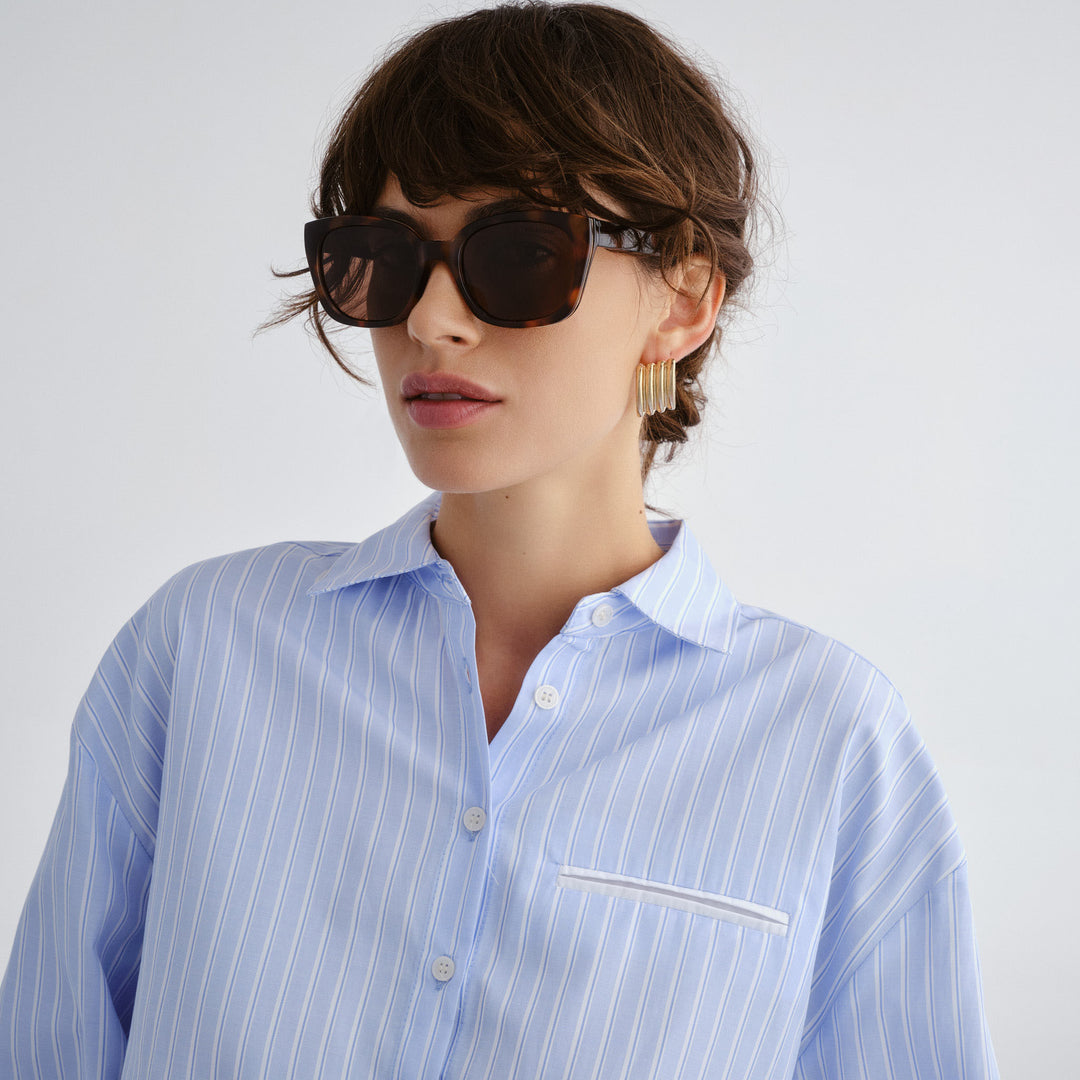 Female model wearing Teneriffe sunglasses in amber tort with gold detailing, front view showcasing fit and frame style