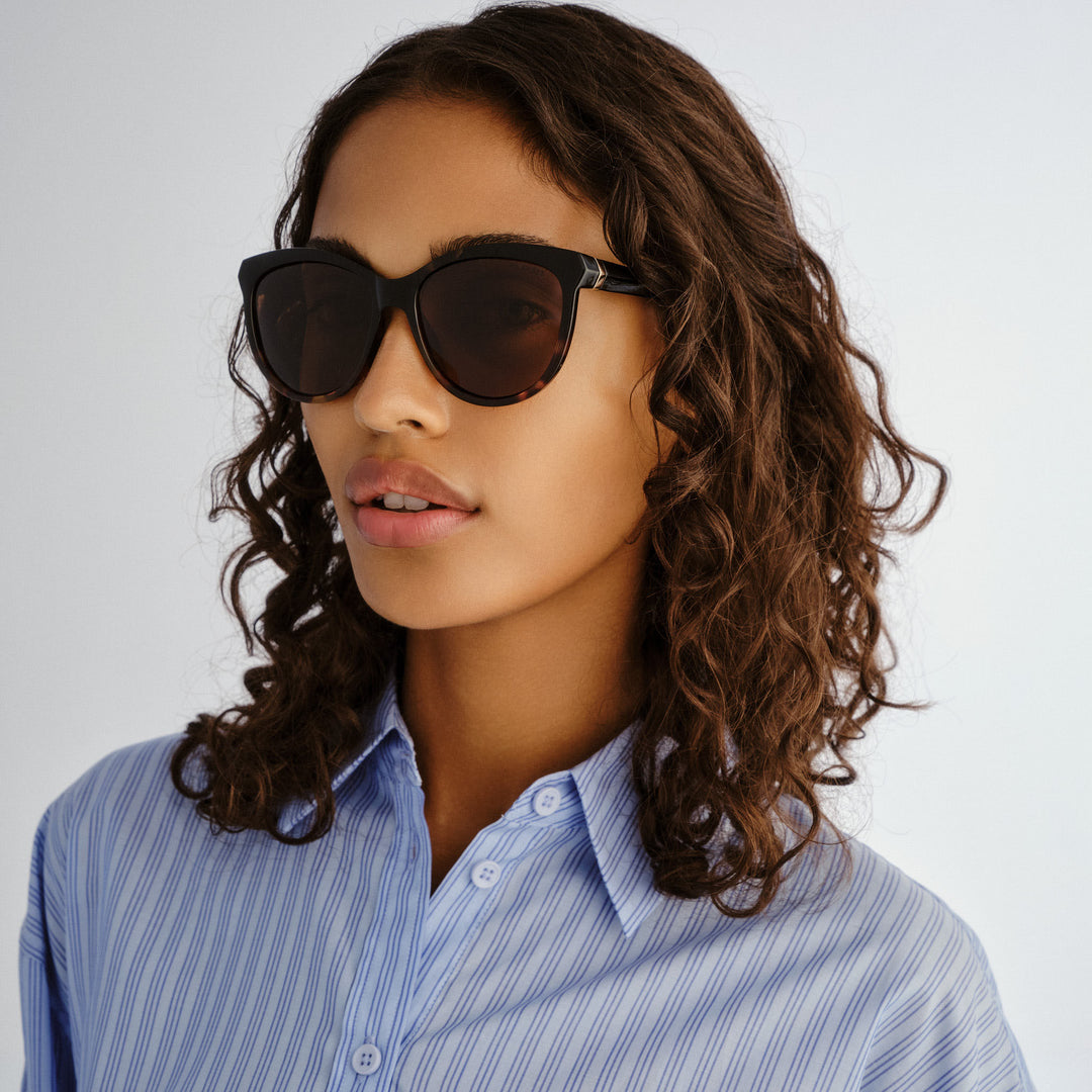 Three‑quarter angle of model wearing Cancer Council Calwell sunglasses in Black/Tort Splice