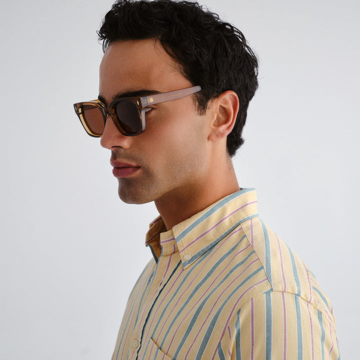Man wearing sunglasses and a striped shirt against a plain background