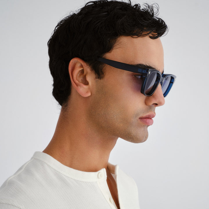 Man wearing Kingscliff blue sunglasses with a neutral background, side profile