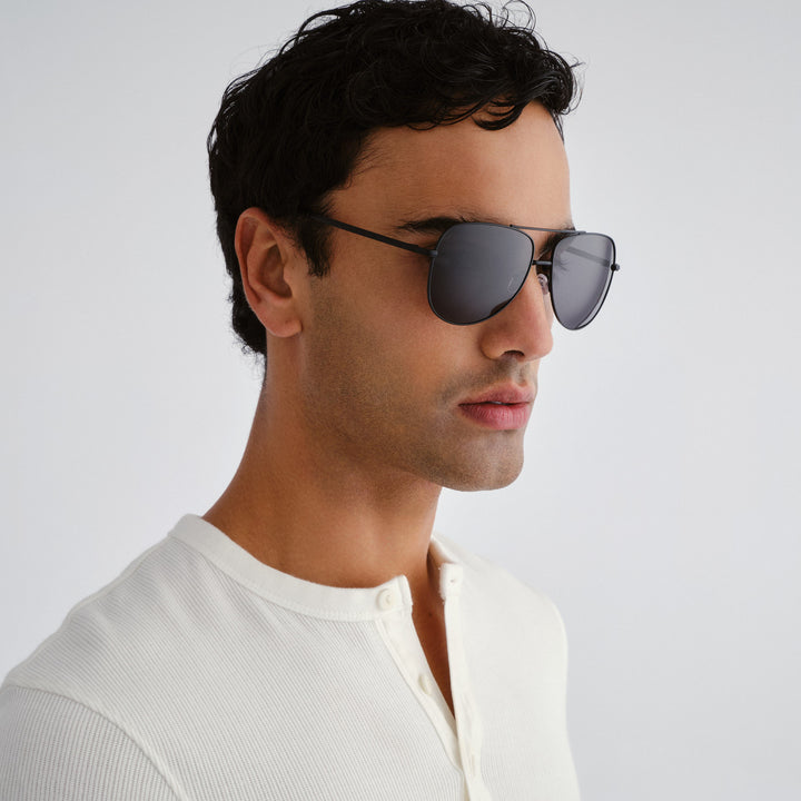 Man wearing dark sunglasses against a light gray background