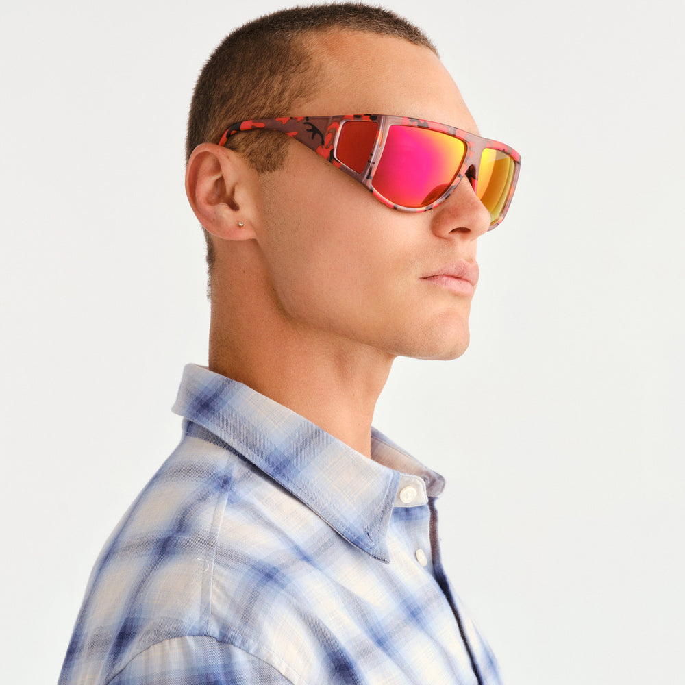 A man wearing red mirrored sunglasses with red and brown camouflage pattern