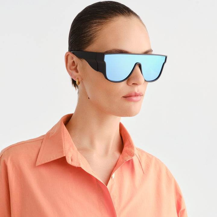 Women wearing Black and blue sunglasses wearing a peach coloured shirt