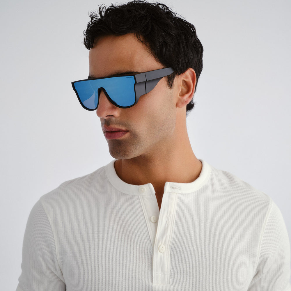 Man wearing futuristic sunglasses with a white shirt on a light gray background