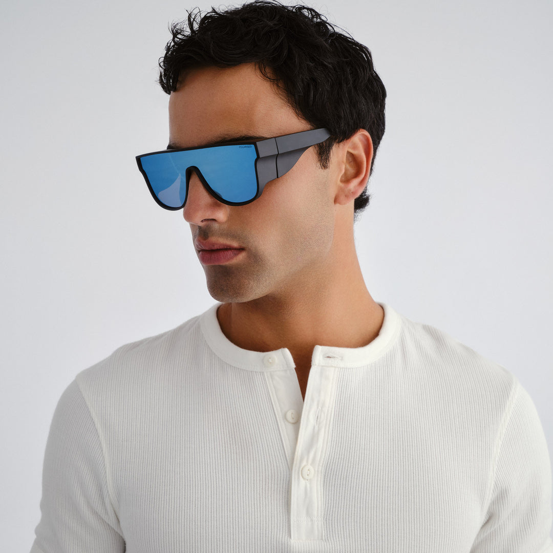 Man wearing futuristic sunglasses with a white shirt on a light gray background