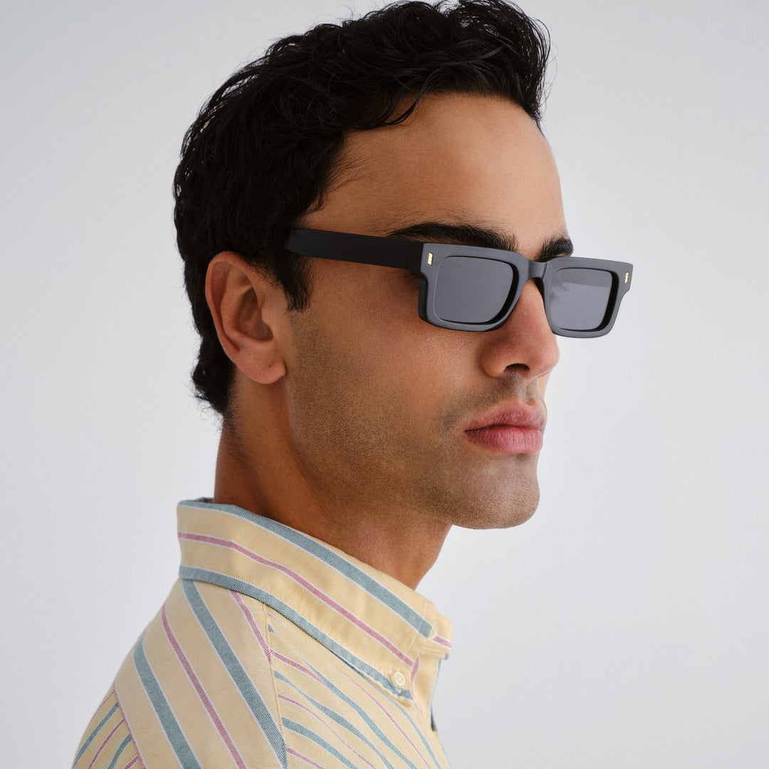 Man wearing black sunglasses with a light gray background