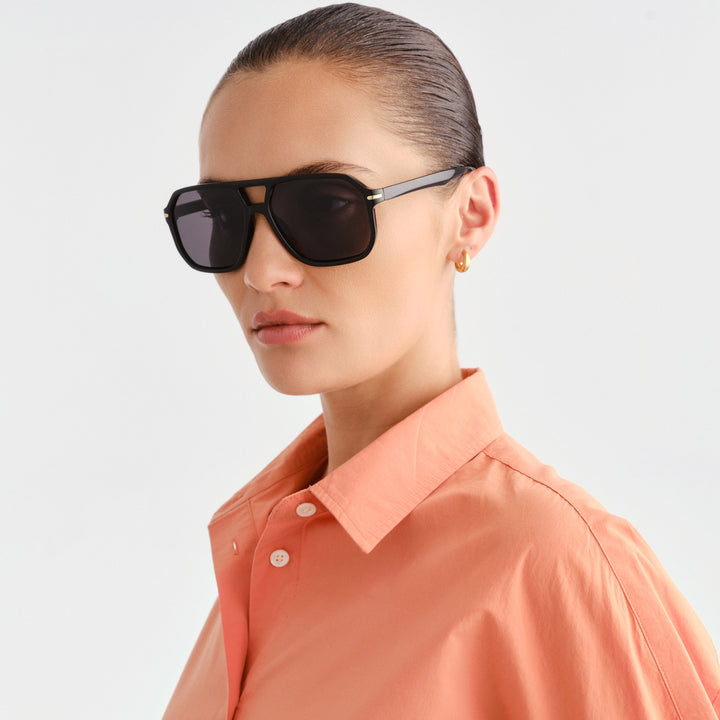 A woman wearing black sunglasses and peach shirt