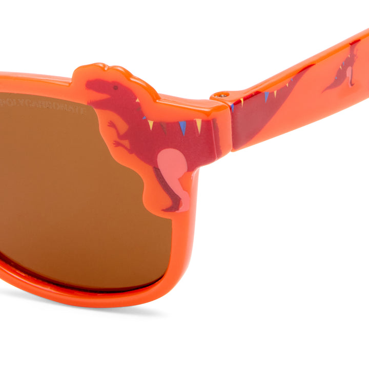 Close-up of bright orange dinosaur-shaped sunglasses with a brown mirrored lens and a small blue accent on the temple arm, shown on a white background.