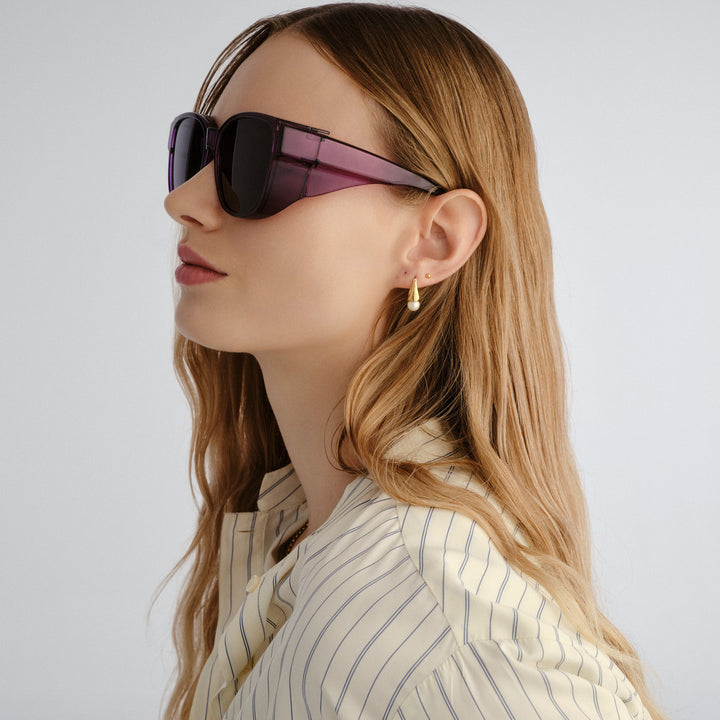 Woman wearing sunglasses and a striped shirt against a plain background
